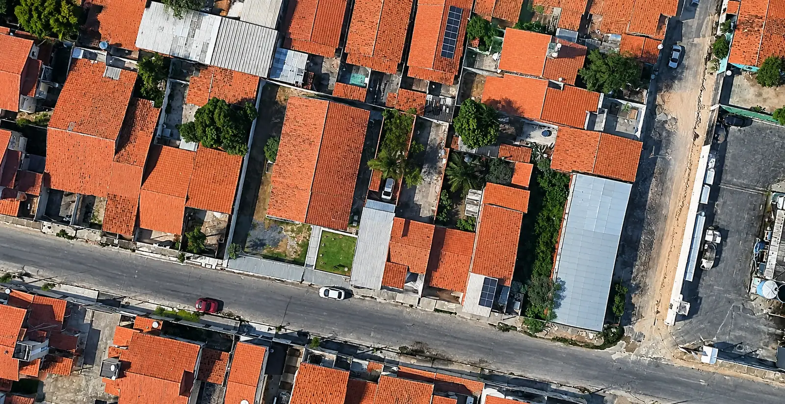 Vista aérea de uma quadra residencial com telhados e a rua em frente