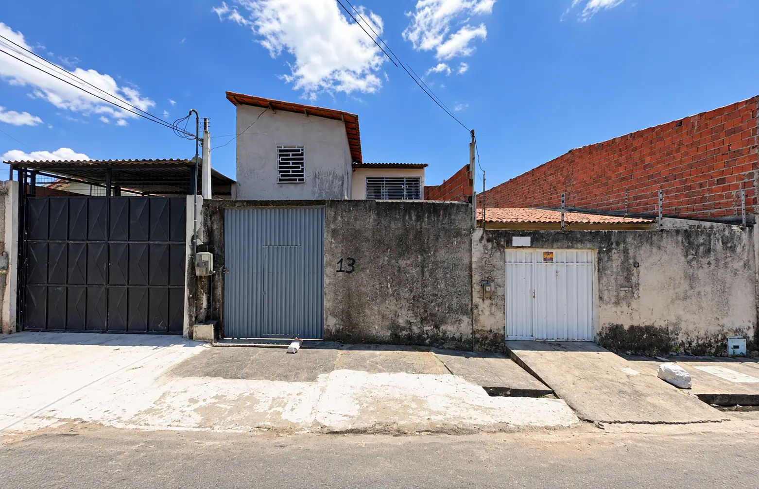 Fachada da Romira: muro com portão cinza de metal ao lado do número 13