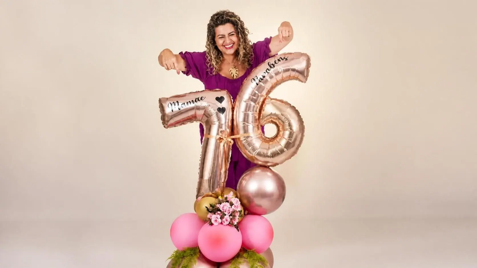 Mulher sorrindo atrás de balões dourados com o número 76